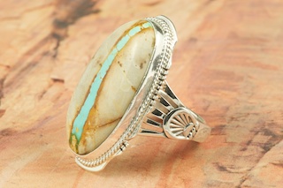 Genuine Boulder Turquoise set in Sterling Silver Ring. The cabachons are of Boulder Turquoise, you can see the veins of Turquoise running through the host rock. The Boulder Turquoise Mine is located in northeast Nevada. It was discovered in 1970 by a Shoshone sheep herder. Production is small due to the remote location and winter weather. Boulder Turquoise is valued for both it's beauty and rarity. Every stone is unique. Created by Navajo Artist Larson Lee. Signed by the artist.